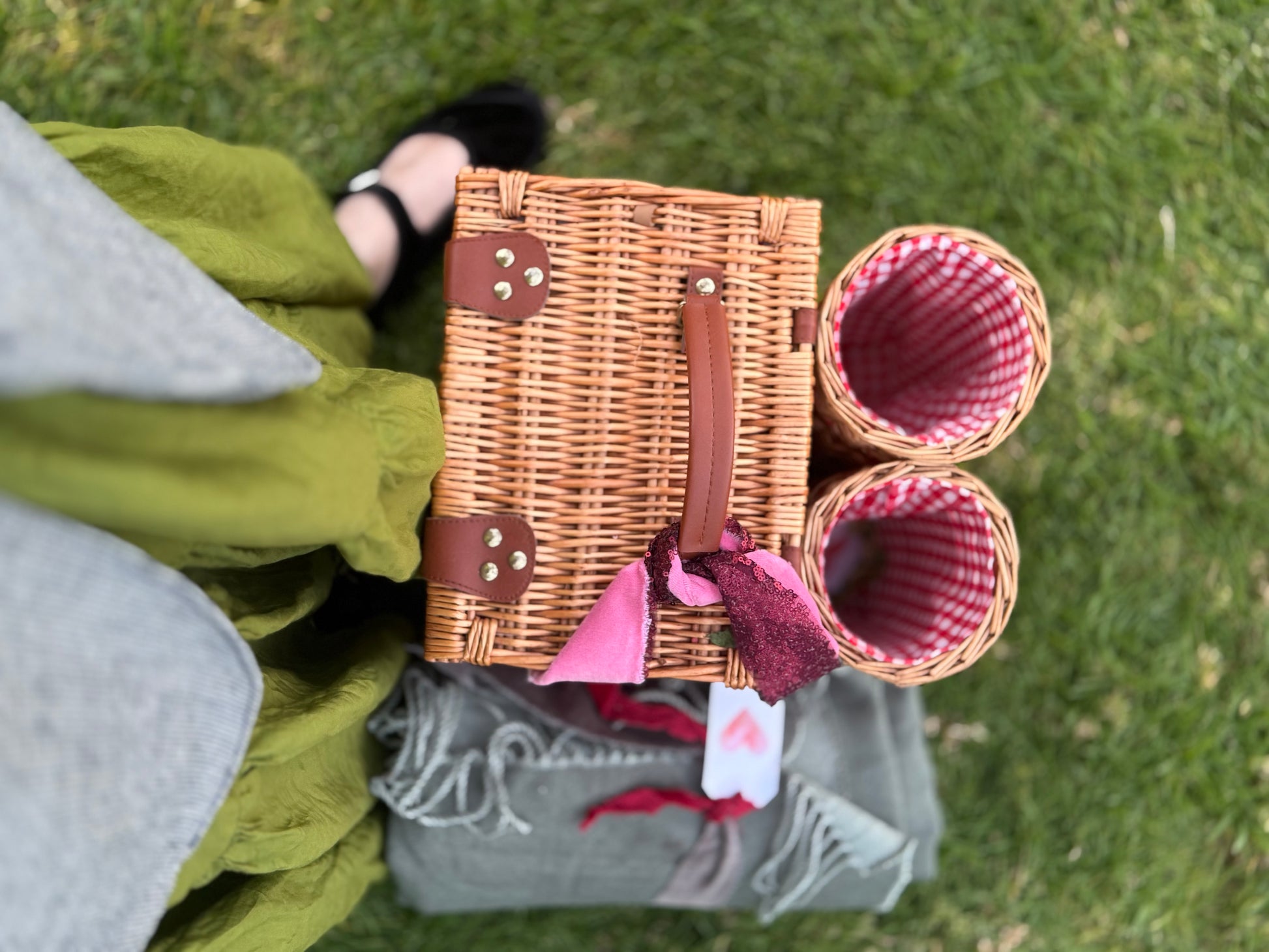 Wicker picnic basket with checkered fabric on a grassy surface.  Blanket.