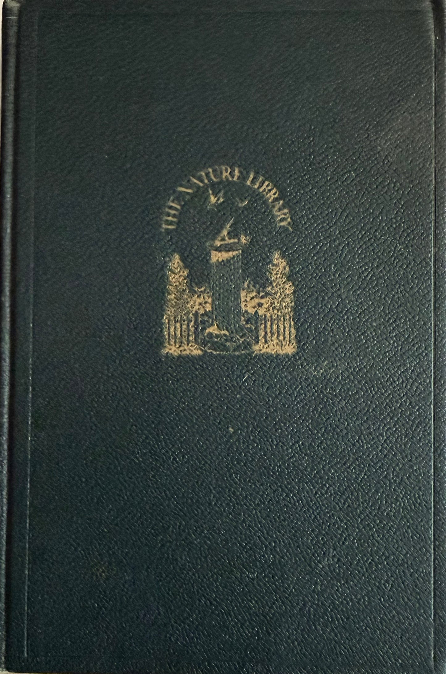 A dark green textured leather-bound book with gold foil embossed lettering reading 'THE NATURA LIBRARY' and a crest emblem on the front cover. topic Garden Flowers