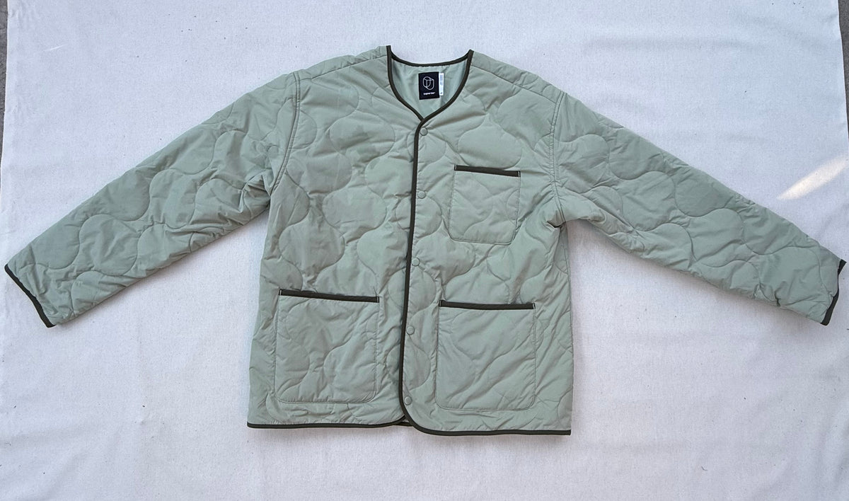 Sage green quilted jacket with olive piping, snap front and three patch pockets, laid flat
