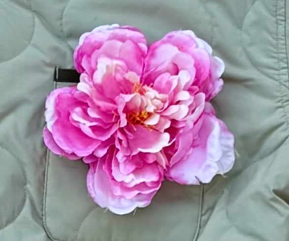 Pink peony flower pin, about 6 inches across, on a sage quilted jacket pocket
