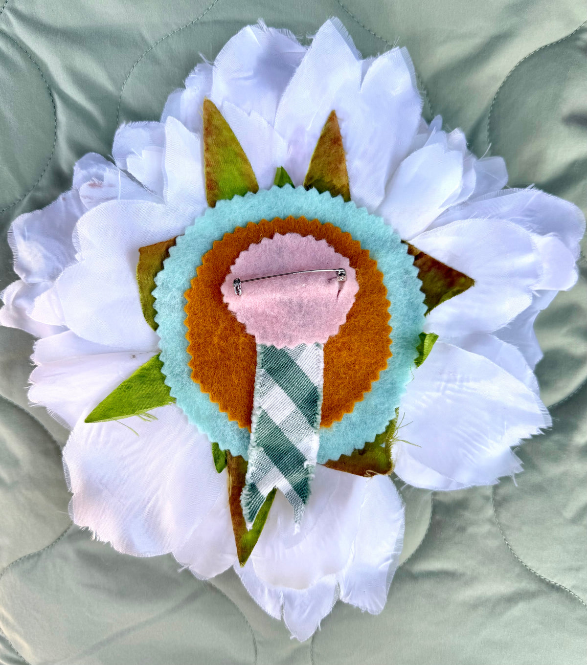 Back of the Evelyn flower pin: layered pink, mustard and aqua felt rosette with green gingham ribbon and pin back